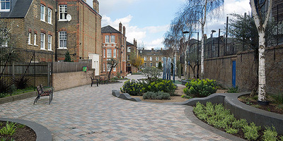 View along a walk with sculptures and plant and houses each side