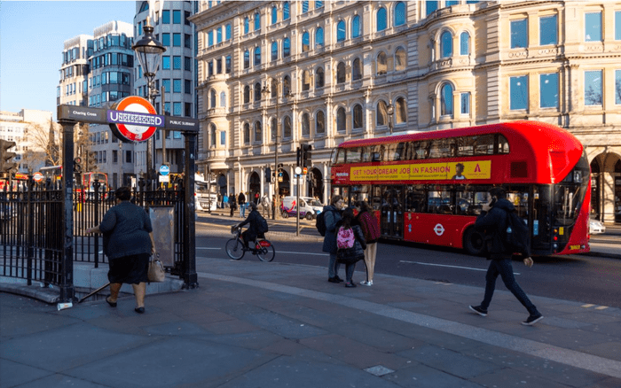 London Bus driving through a London street next to a Tube station